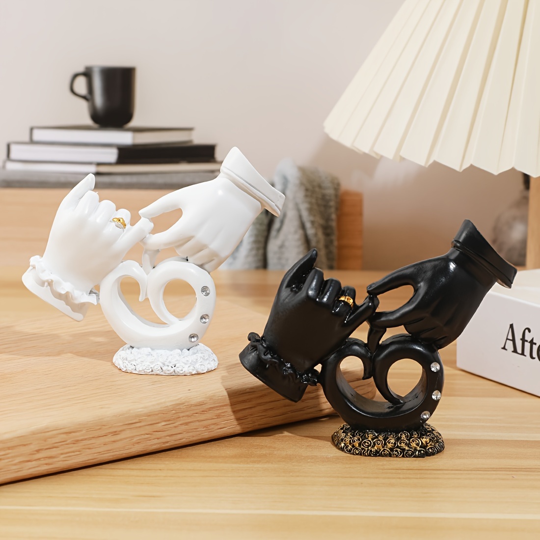 Decorative figurines of hands holding interlocking rings on a wooden surface.